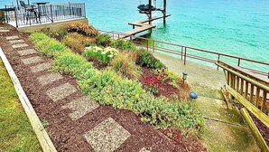 Une promenade en bord de mer avec une terrasse en bois, un petit quai pour bateaux et une vue sur la mer.