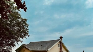 Une maison avec une cheminée en pierre, un porche et une vue sur la mer.