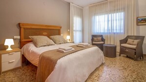 Ein Hotelzimmer mit einem großen Bett, einem Nachttisch, einem Sessel und einem kleinen Tisch.
