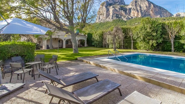 Ein Poolbereich mit Liegestühlen, einer Pergola und Blick auf einen Berg.