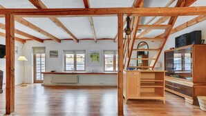Une pièce spacieuse avec des poutres apparentes, une grande fenêtre, un radiateur et un meuble en bois.