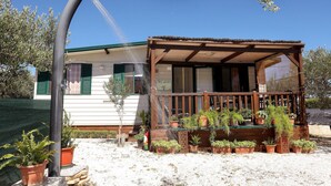 Un espacio de estar al aire libre con techo, banco de madera y plantas en macetas.