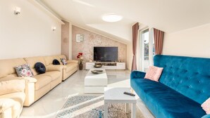 Una sala de estar moderna con un sofá color beige, un sofá azul, un televisor de pantalla plana y una mesa de centro.