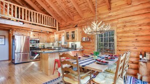 Una cabaña de madera espaciosa con cocina, comedor y habitación en loft.