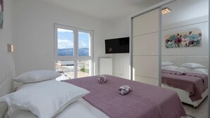 Une chambre avec deux lits, une télévision et une grande fenêtre.