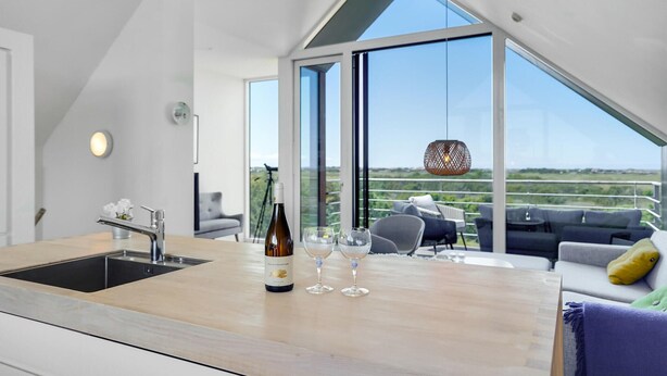 A modern kitchen with a large island, a wine bottle, and glasses. - 4 bedroom stunning home in Skagen (Skagen)