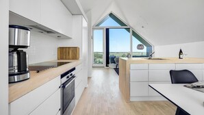 A modern kitchen with a large island, a built-in oven, and a view to the outdoors. - 4 bedroom stunning home in Skagen (Skagen)