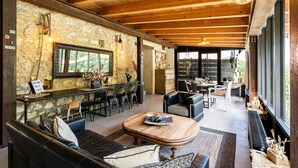 Un interior acogedor con paredes de piedra, vigas de madera, una zona de bar y un comedor.