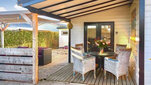 A covered patio with wicker chairs, a table, and a vase of flowers. - Beautiful home in Sint-Annaland (Sint-Annaland)