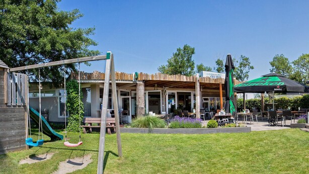 A patio area with outdoor seating, a swing set, and a covered seating area with a Heineken umbrella. - Beautiful home in Sint-Annaland (Sint-Annaland)