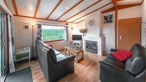 A cozy living room with a fireplace, a sofa, a television, and a dining table. - Beautiful home in Sint-Annaland (Sint-Annaland)