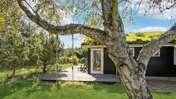 A wooden deck with a swing, a small shed, and a lawn. - 3 bedroom cozy home in Blokhus (Blokhus)