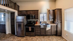 A modern kitchen with stainless steel appliances, dark wood cabinets, and a granite countertop.