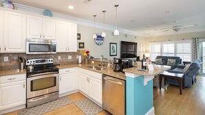 Una cocina moderna con electrodomésticos de acero inoxidable, armarios blancos y una pared de acento azul.