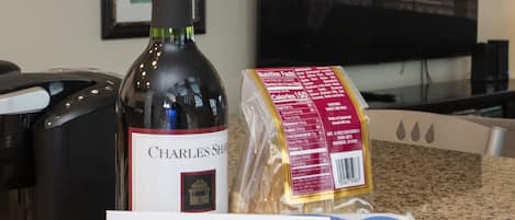 Un letrero de bienvenida, una botella de cerveza Charles Shaw y una bolsa de pan sobre la encimera de la cocina.