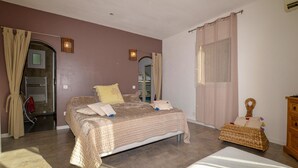 A bedroom with a bed, a bedside table, a dresser, and a window with curtains.