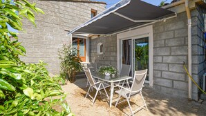 A patio with a table and chairs, a covered area, and a stone wall.