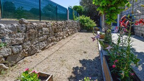 A garden with a stone wall, flower beds, and a dog.