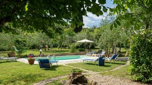 Um quintal com piscina, espreguiçadeiras e churrasqueira.