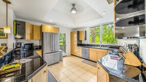 Une cuisine moderne avec des plans de travail noirs, des appareils en acier inoxydable et des meubles en bois.