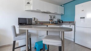 Eine moderne Küche mit weißen Schränken, einer Mikrowelle, einer Kaffeemaschine und einem Spülbecken.