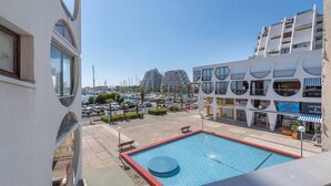 Ein modernes Gebäude mit Pool, einer Marina und Hochhäusern im Hintergrund.