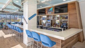 Een bar met een aanrecht, blauwe barstoelen en een verscheidenheid aan flessen en glazen.