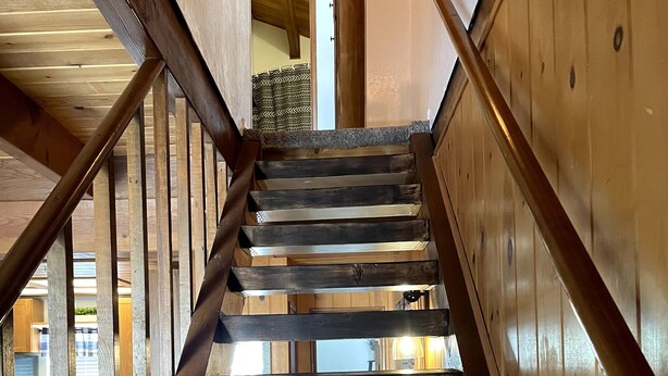 Una escalera de madera con barandilla que conduce a un piso superior.