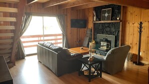 Una sala de estar acogedora con techo de madera, chimenea, sofá y televisor.