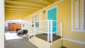 A covered outdoor area with a yellow wall, a turquoise door, and a white railing. - Quiet Oasis Near the Colorado River STR (Bullhead City)
