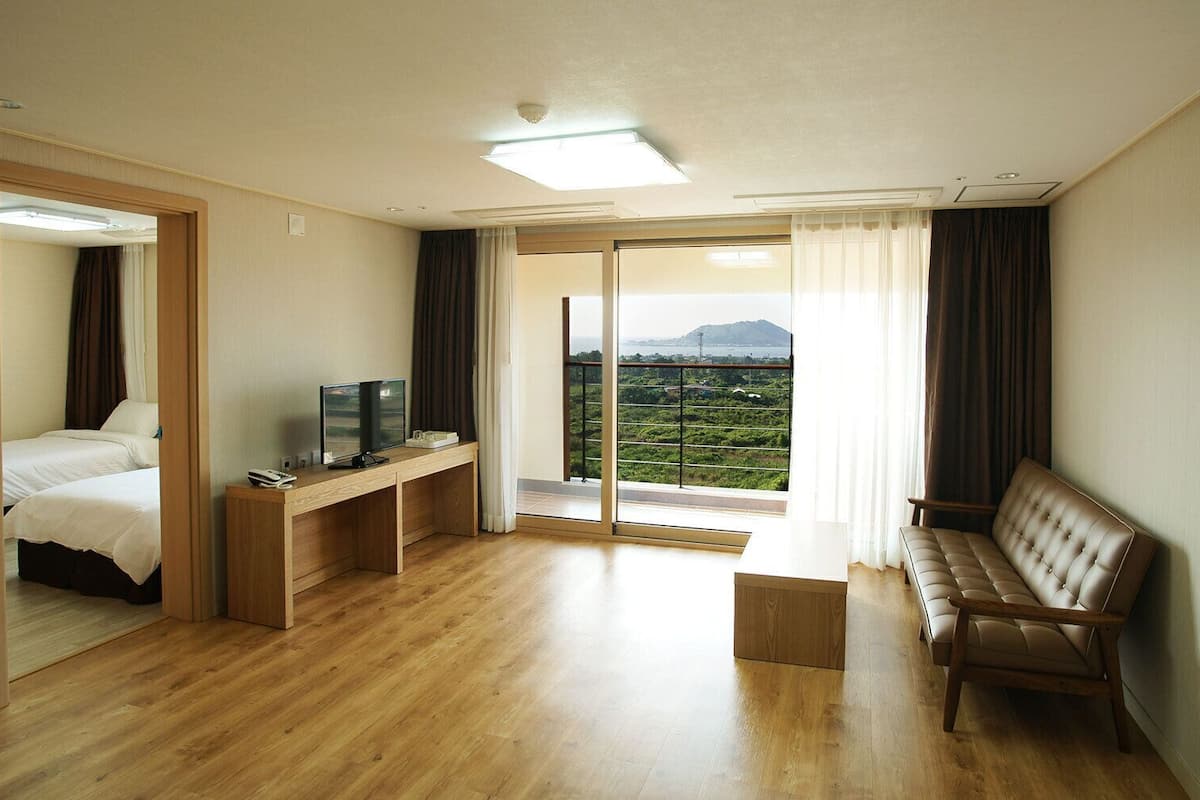 Une chambre d’hôtel avec un bureau en bois, un lit, un canapé et un balcon avec vue.