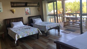 Una habitación con dos camas de madera, una mesa de madera y un ventanal con vistas al exterior.