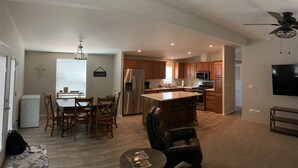 Ein geräumiges Wohnzimmer mit Essbereich, eine Küche mit Holzausstattung, einer großen Kochinsel und einem Deckenventilator.