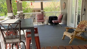 Ein überdachter Patio-Bereich mit Holztischen und -stühlen, einem Grill und Lichterketten.