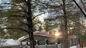 Eine Hütte mit überdachter Terrasse, umgeben von Schnee und Bäumen.
