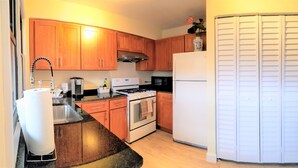 A kitchen with wooden cabinets, a stove, a refrigerator, and a sink.
