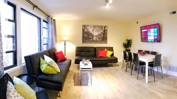 A living room with a sofa, coffee table, and dining area with chairs and a table.