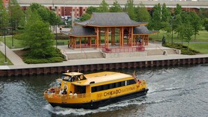 A yellow boat named "Chicago Water Taxi" with passengers, moving on a river.