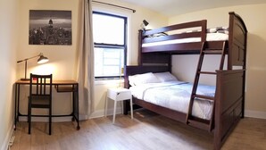 A bunk bed room with a desk, chair, and a lamp.