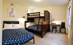 A bedroom with two bunk beds, a desk, and a chair.