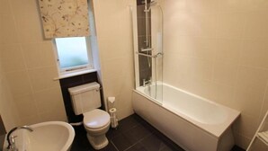 Un baño con inodoro, bidé, lavabo y ducha con mampara de vidrio.