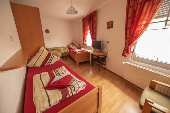 A small, cozy room with a bed, a desk, and a chair.