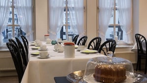 Un coin repas avec une table mise pour le repas, des chaises et un gâteau présenté sur un plateau en argent.