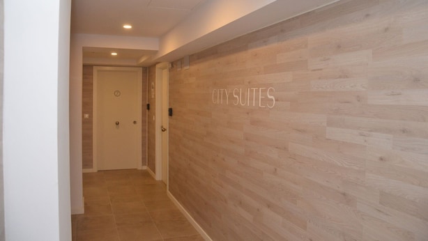 A hallway with a wooden wall and a door labeled "CITY SUITES". - City Suites Apartments (Valencia)