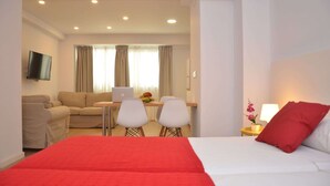 A hotel room with a bed, a desk with a laptop, a sofa, and a TV. - City Suites Apartments (Valencia)