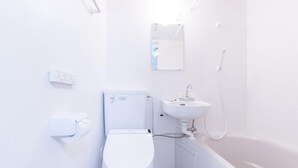 A modern bathroom with a toilet, sink, and bathtub. - Oyo 44646 Wa Style Tokyo (Kawaguchi)