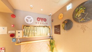 A reception area with a wooden reception desk, a clock, and a wall-mounted sign with the name 'OYO RYOKAN'. - Oyo 44646 Wa Style Tokyo (Kawaguchi)