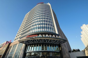 A tall hotel building with a prominent sign reading "Hyatt" and "Hilton" indicating it is part of the Hilton hotel chain.