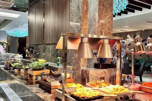 Un buffet proposant une variété de plats, avec une colonne centrale agrémentée de luminaires.