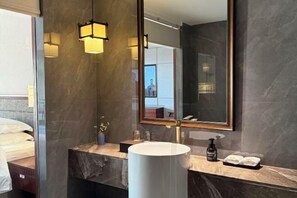 Une salle de bain moderne avec un grand miroir, un lavabo rond et un plan de toilette en marbre.